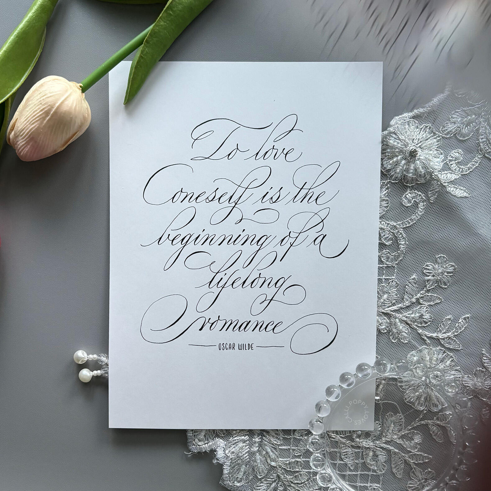 ชิ้นงาน "To love oneself is the beginning of a lifelong romance." คำกล่าวโดย Oscar Wilde ศิลปินนำมาออกแบบตัวอักษรในรูปแบบ Calligraphy โดยใช้ Pointed pen หรือ Dip pen (ปากกาจุ่มหมึก) วาดตัวอักษรออกมาบนกระดาษ