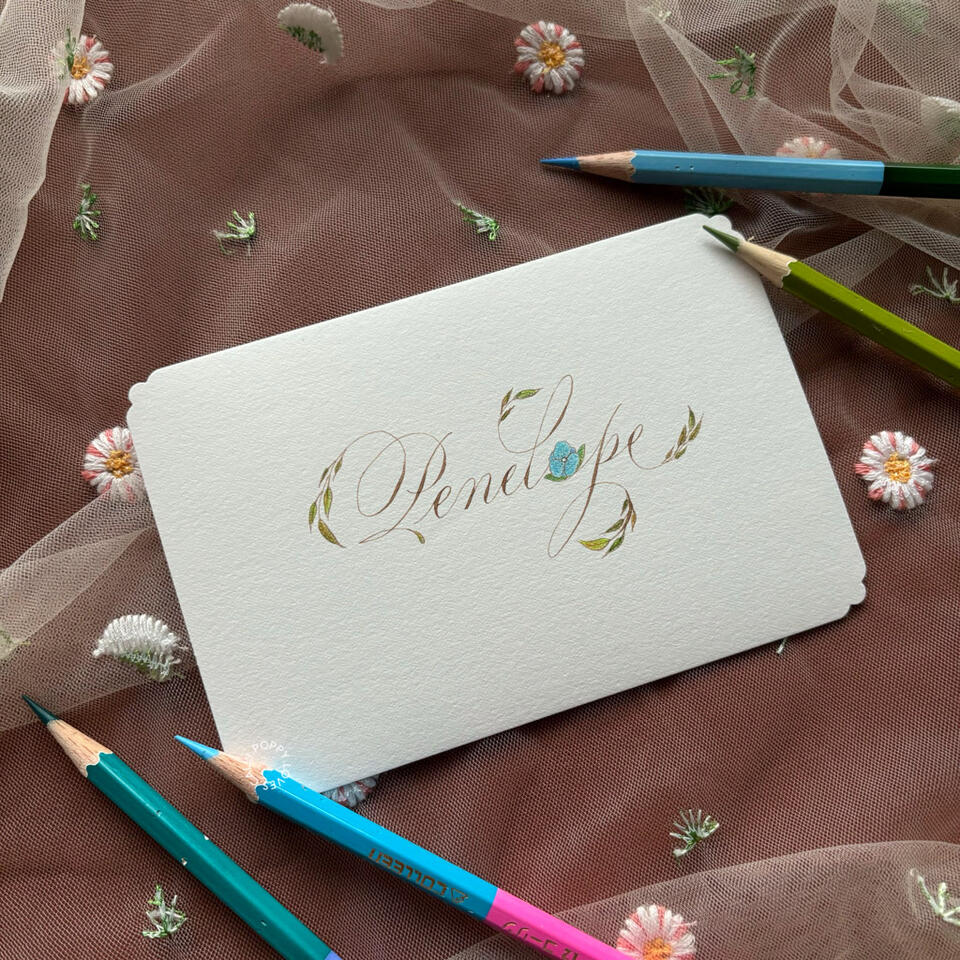 ออกแบบชื่อ "Penelope" ให้ออกมาวิจิตรใน Calligraphy Style ของ Poppy.Loves.Calli โดยอ้างอิงจากตัวละคร Penelope Featherington จากซีรีส์ Bridgerton ของ Netflix ตกแต่งด้วยดอกไม้และพืชพรรณที่ค่อยๆ เบิกบานตามคาแรกเตอร์ของเพเนโลพีที่ค่อยๆ เปล่งประกายจากไม้ประดับใน