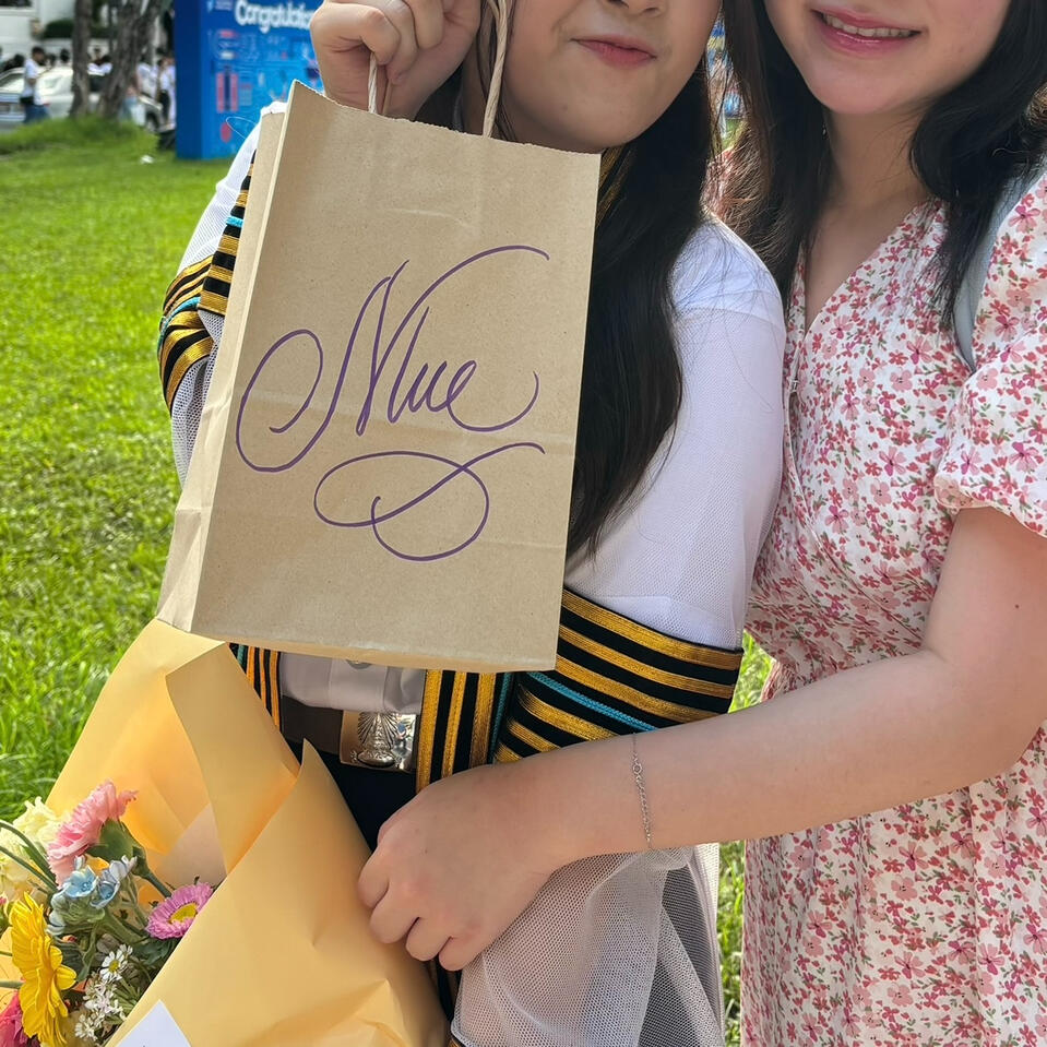 ภาพการมอบถุงของขวัญที่มีการเขียนชื่อผู้รับในสไตล์ Calligraphy ให้บัณฑิตที่จบการศึกษาประจำปี 2567